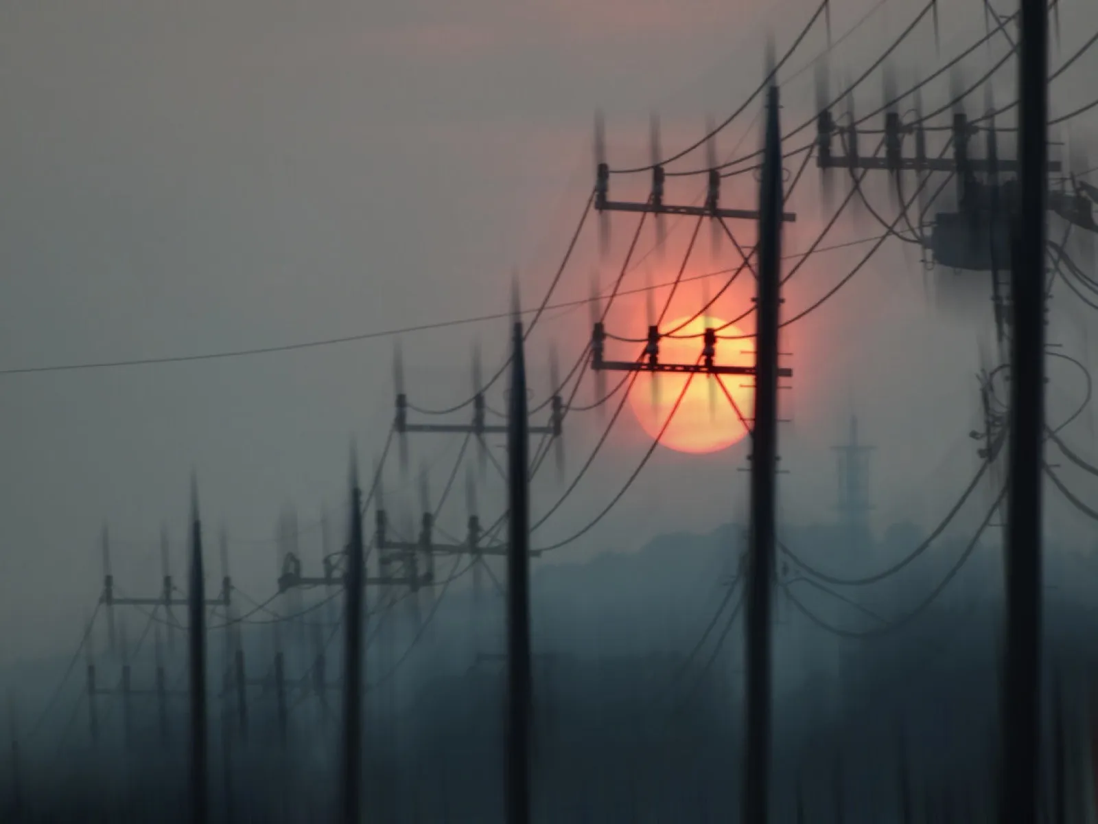 Power lines against a hazy red sun
